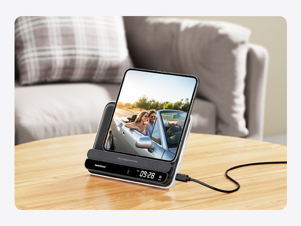 Smartphone displaying video content positioned on a wooden stand or dock with connecting cable visible.
