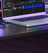 Laptop displaying audio waveform or sound editing software interface with blue and white visualization against dark background.