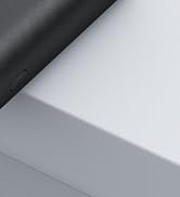 Close-up of a corner where two surfaces meet, showing a black textured material on top and a smooth light gray surface below.
