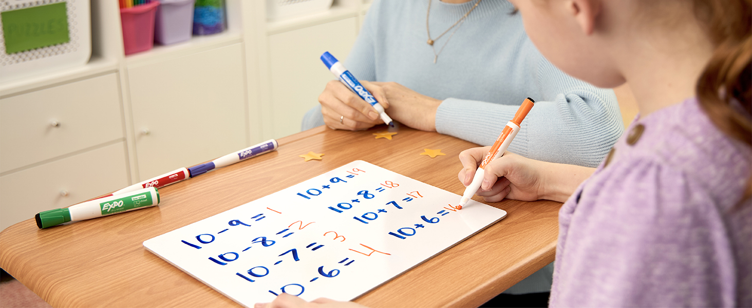 girl doing math homework on dry erase board