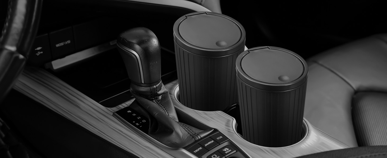 Car interior showing automatic transmission gear shifter and two circular cup holders with ribbed black covers. Center console area visible in grayscale image.