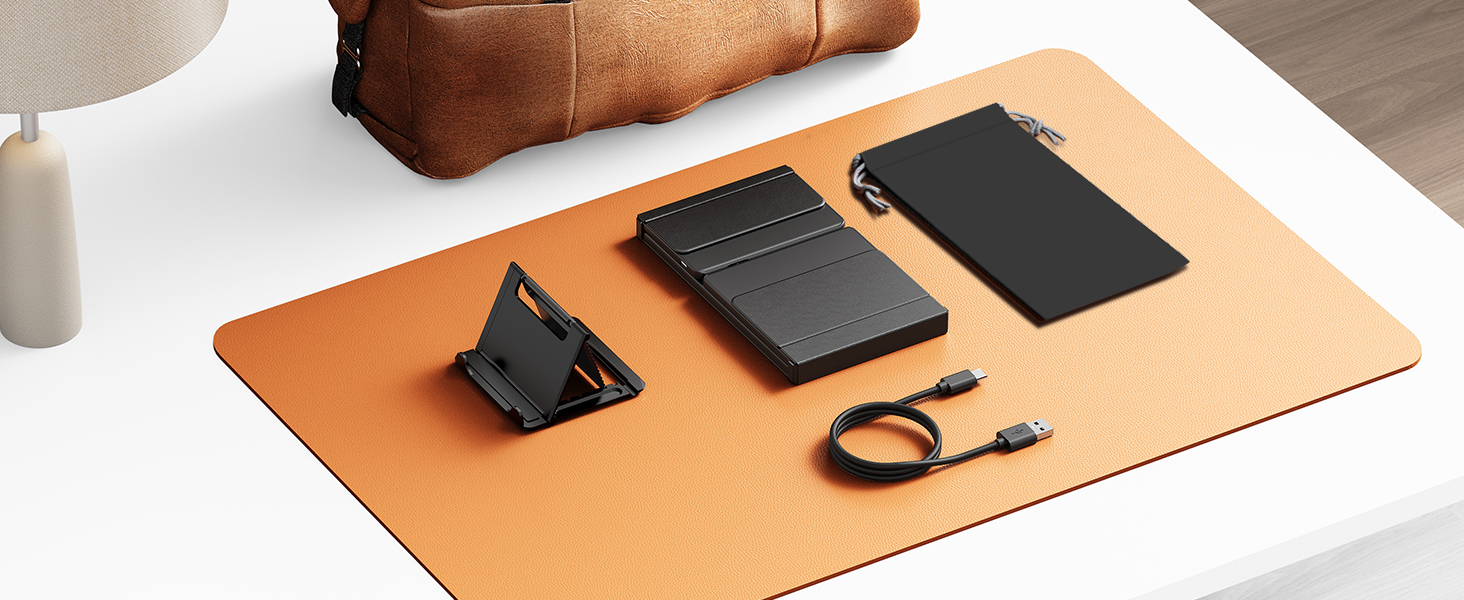 Desktop scene featuring a leather desk mat in tan/brown color with electronic devices and accessories neatly arranged on its surface.