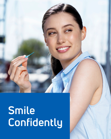 A woman cleaning between her teeth with interdental dental tools. Text reads: “Smile confidently.”