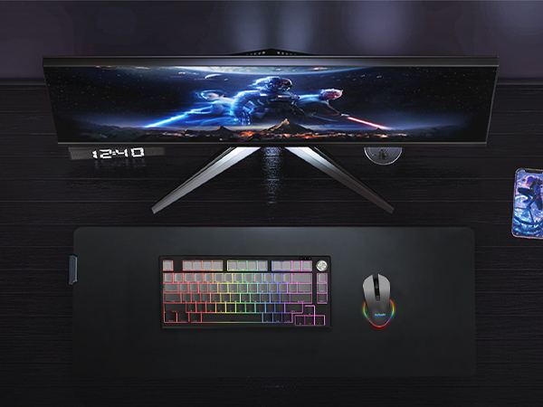 Modern gaming desk setup with ultrawide monitor displaying blue lighting effects, RGB gaming keyboard, and gaming mouse on black surface.