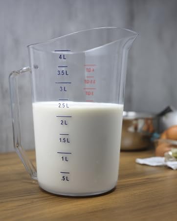 4 Liter measuring cup with milk, in a kitchen with various kitchen tools in the background.