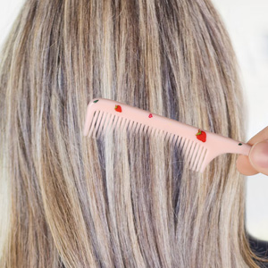 Close-up of long blonde highlighted hair with hand touching strands, showing texture and color blending of hair extensions or dyed hair treatment.