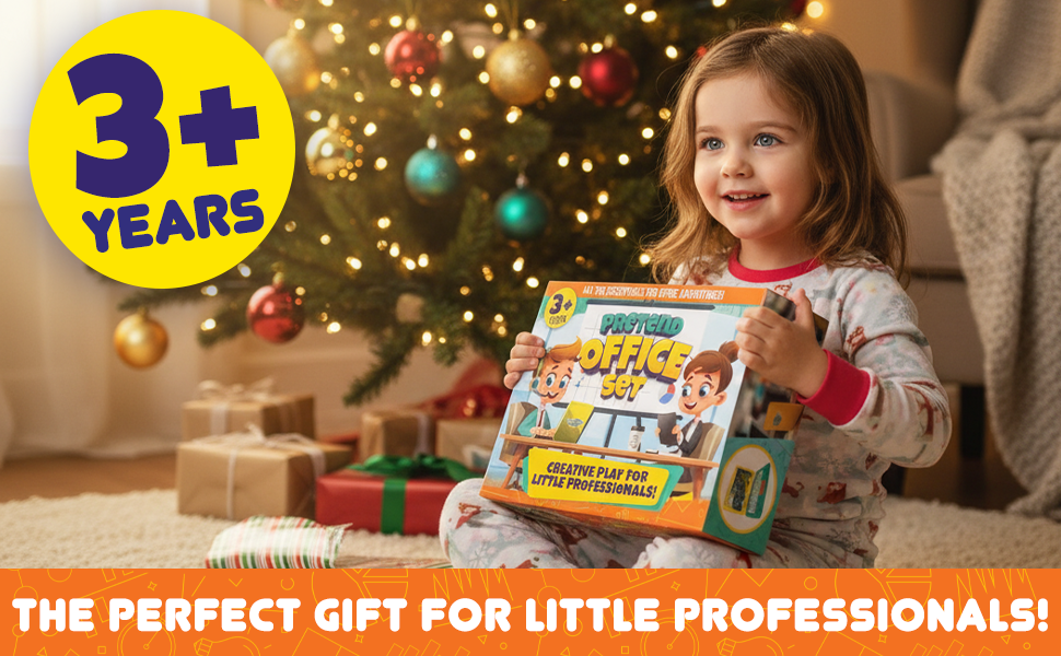 Smiling girl holding Pretend Office Set box near Christmas tree, surrounded by gifts.