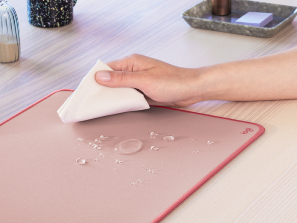 A zoom of a hand cleaning the Desk Mat