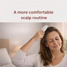 Woman using an electric scalp care brush at home