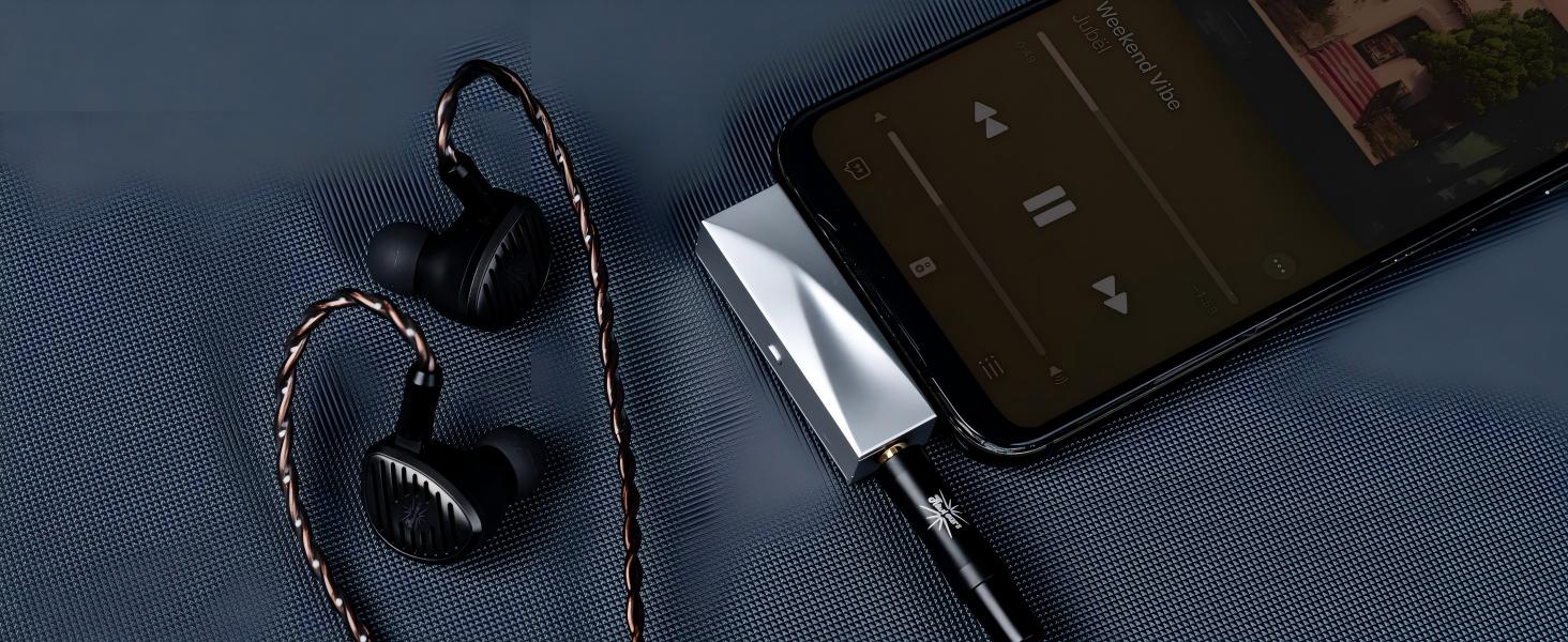 Black wireless earbuds with braided white and black cable connected to smartphone displaying screen, positioned on blue fabric surface.