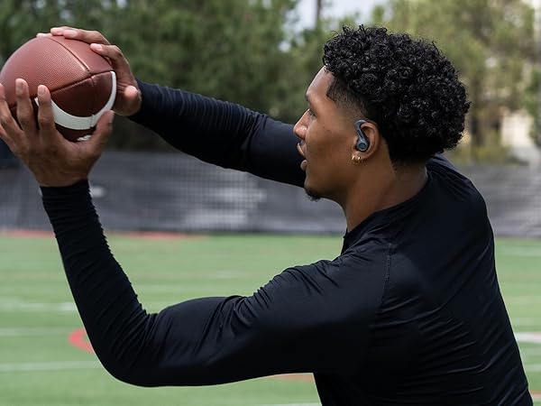 Athlete catching football while wearing jbuds sport