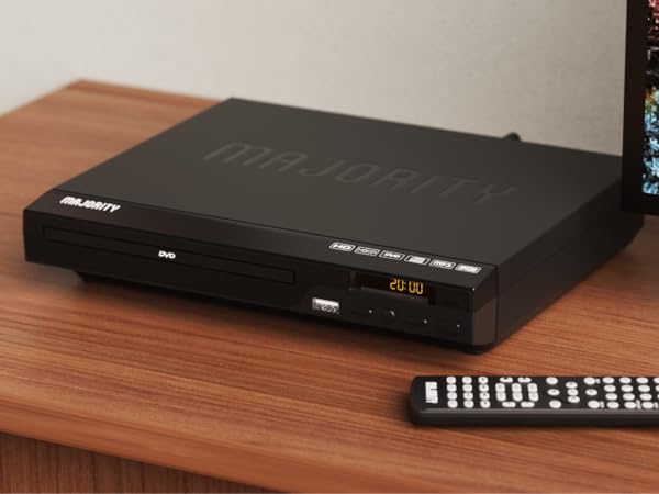 Majority region free dvd player on wooden shelf in living room. Display shows time