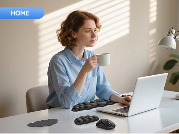 Ergonomic keyboard wrist rest on desk with laptop. Black cushioned design in segments. Mouse pad with similar cushioned design visible nearby.