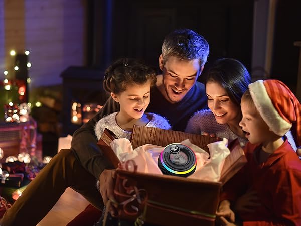 Group gathering in dimly lit setting with various electronic devices, showing social interaction in evening/night environment with decorative lights in background.