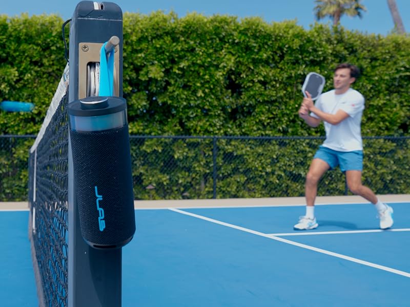 Go party speaker hanging on its carrying strap on a pickelball court divider