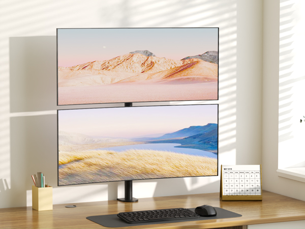 Dual monitor setup on wooden desk, displaying mountain landscapes on both screens, with wireless keyboard and decorative accessories.