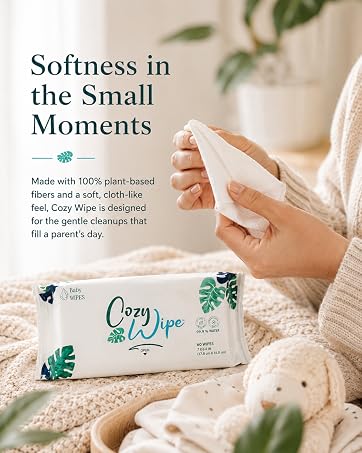 Hand holding a soft baby wipe with a Cozy Wipe pack in a warm nursery.