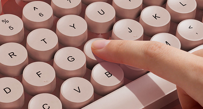 Finger pressing wine red round keycaps on wireless keyboard for smooth responsive typing feel