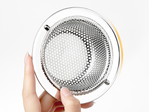 Close-up of stainless steel kitchen sink strainer basket with perforated design and visible rim detail held by hand.