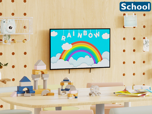Classroom setting with pegboard wall, colorful rainbow artwork, wooden blocks, and toys on table. 'School' sign visible in corner.
