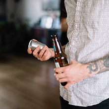 person holding bottle opener in hand with beer