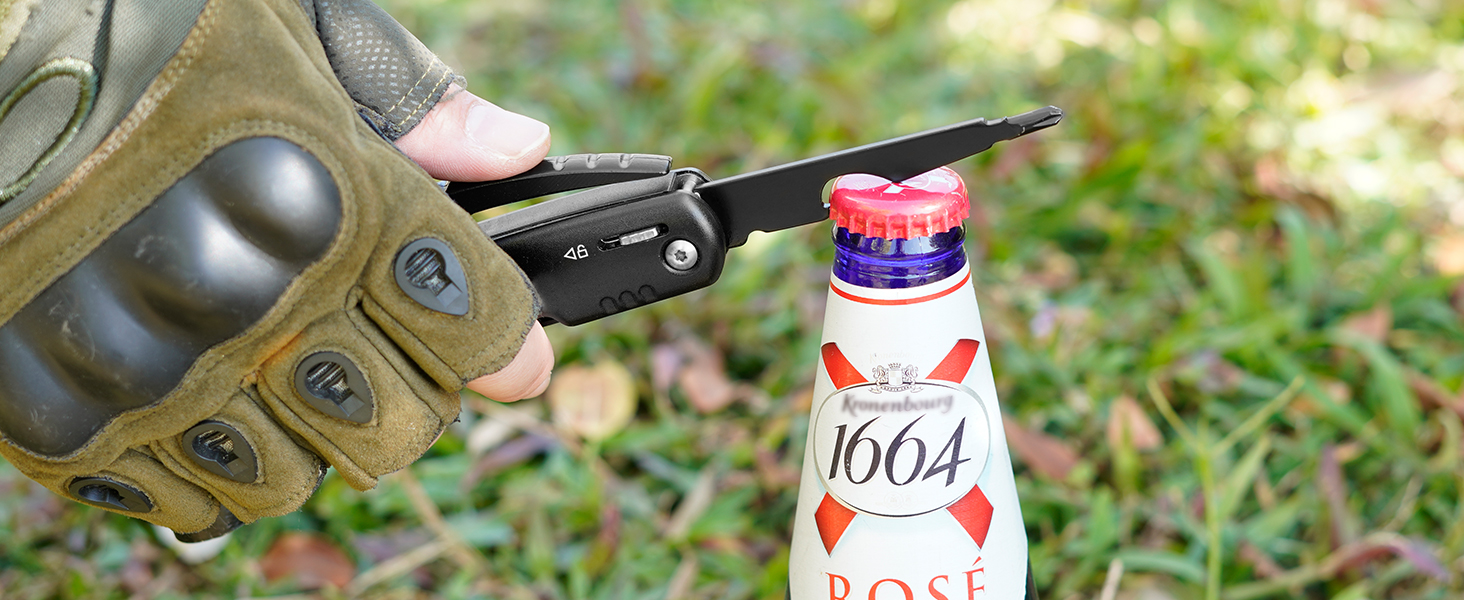 Gloved hand using bottle opener on a 1664 beer bottle outdoors on grass.