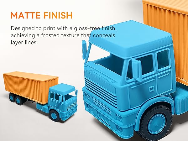 Two 3D-printed toy trucks with matte finish. Large blue truck with orange container in foreground, smaller blue truck with orange trailer in background. Demonstrates gloss-free, frosted texture.