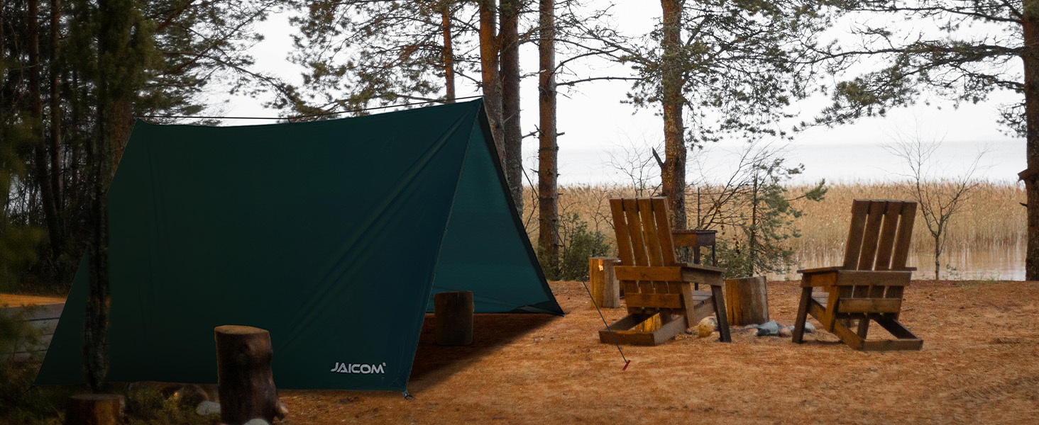 Camping scene with green tent and two wooden chairs. Pine trees in background, suggesting a forest or lakeside setting.