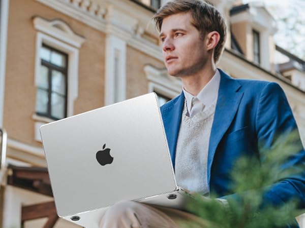 Silver MacBook laptop being used outdoors against architectural backdrop, displaying slim profile and characteristic aluminum design.