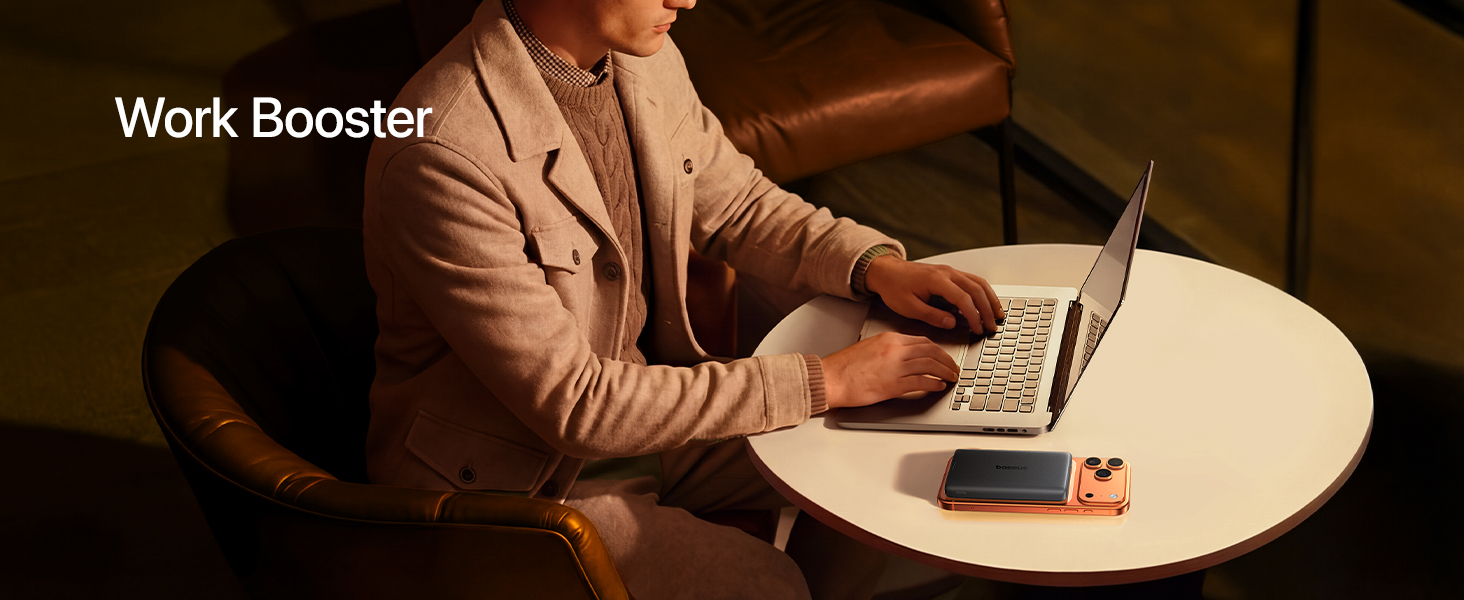 Text reads 'Work Booster'. Shows person working at round table with laptop in modern office setting with natural lighting.