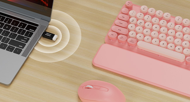 USB receiver plugged in laptop connects pink wireless keyboard mouse combo with wrist rest on desk