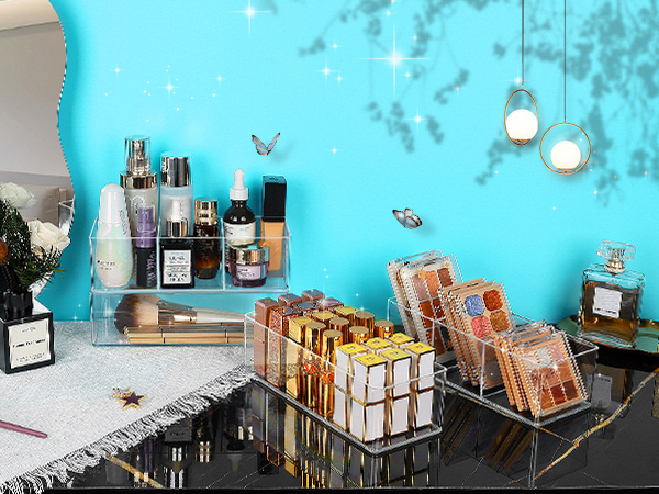 Decorative display setup featuring perfume bottles and books arranged on concrete surface against turquoise wall. Hanging pendant lights and butterfly decorations visible in background.