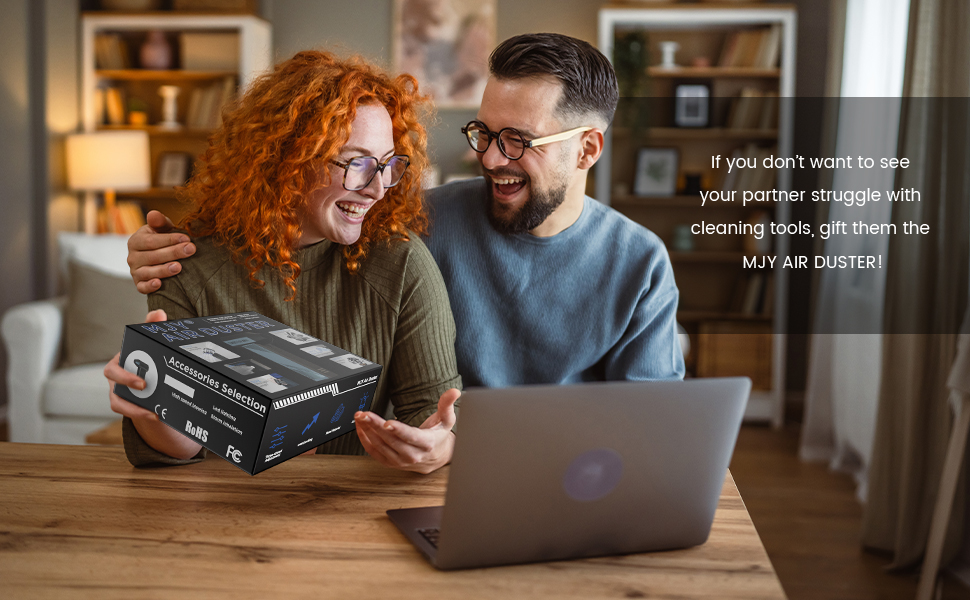 Couple examining a black box labeled 'MLV AIR DUSTER' in a home office setting. Text overlay suggests it as a gift to help with cleaning tasks.