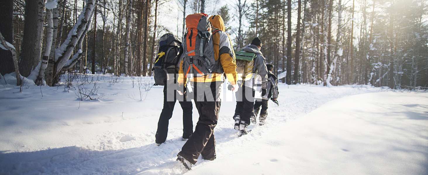 Group of winter hikers traversing through a snowy forest landscape, wearing backpacks and winter gear, walking in single file through sunlit snow-covered terrain.