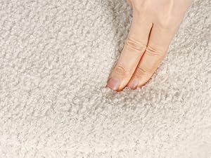 Close-up of fingers touching light-colored carpet or fabric, demonstrating texture or softness.