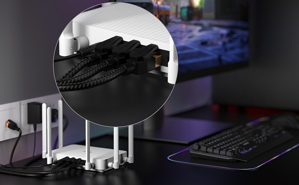 A desk setup with a computer keyboard, monitor, and power outlet. A circular inset shows a close-up of black cable management accessories organizing cords near the wall.