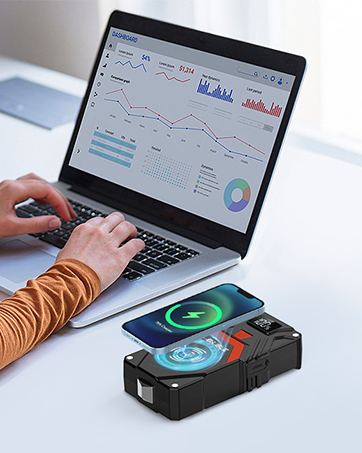 Laptop displaying analytics graphs and charts, with a phone wireless charging on a black pad in foreground.