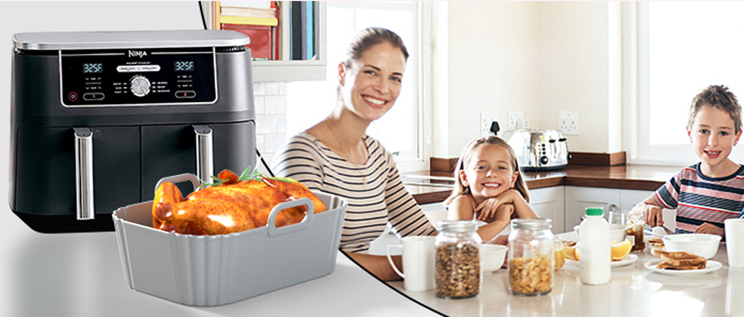 Kitchen scene with air fryer containing fried chicken. Family seated at table with breakfast items and beverages.