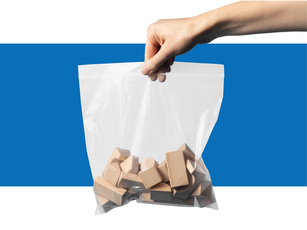 An extended hand holds a bag of wood building blocks in a poly bag over a blue and white background.