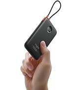 Hand holding a black rectangular power bank with digital display. Features orange loop, USB ports, and '10000mAh' capacity label. Compact and portable design.