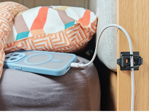 Phone charging cable secured by bed.