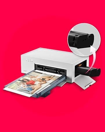 White photo printer with open paper tray, printing a color photograph. Inset image shows black ink cartridge being inserted into the top of the printer.