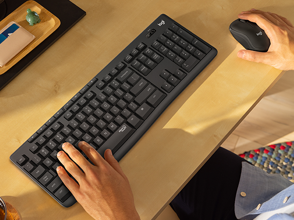 a man typing on the keyboard of mk295 wireless keyboard and mouse graphite combo
