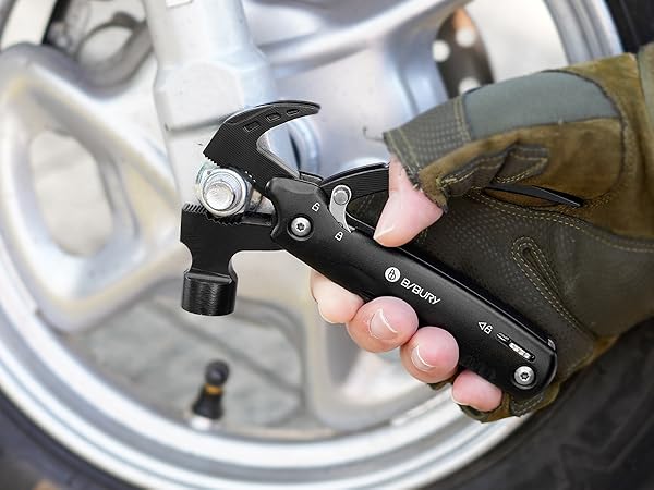 Black multi-tool hammer device with folding handle being held against metallic surface, featuring claw hammer head and utility functions.