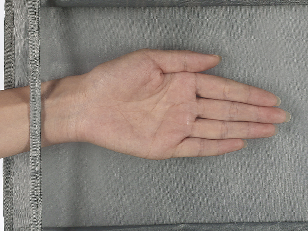 Hand pressing against a light gray fabric surface, demonstrating texture or softness of the material.