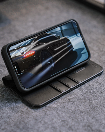 Black leather smartphone wallet case open to display screen showing sports car image. Case features card slots and stand functionality.