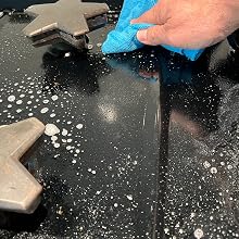 Hand with microfiber wiping cooktop
