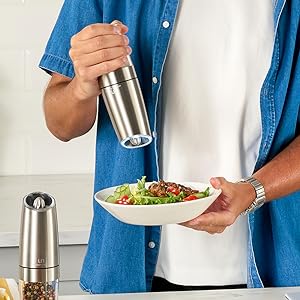 Image of man holding the gravity grinder and adding pepper to a colorful and delicious salad