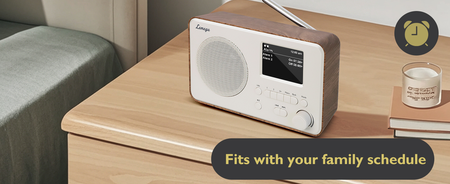 Text reads 'Fits with your family schedule'. Modern white electronic device displayed on wooden surface alongside decorative items.