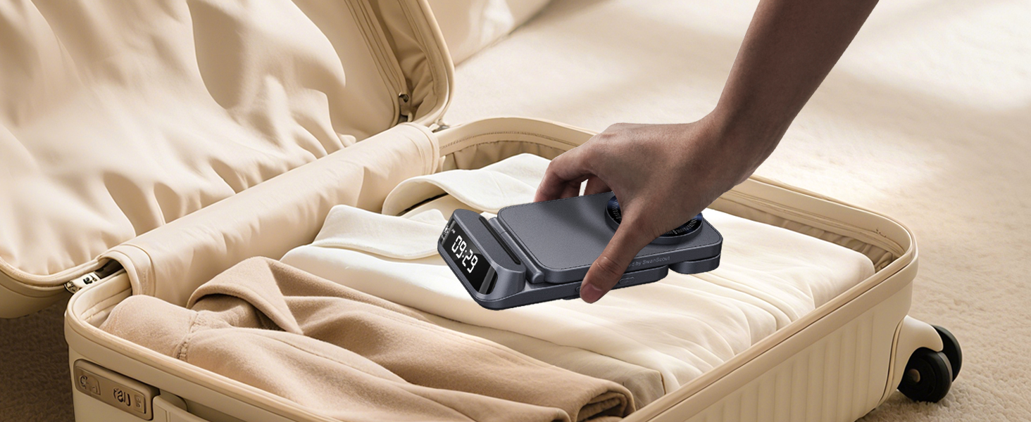 Hand placing a small black electronic device with a digital display into a beige suitcase. The device appears to be a portable charger or power bank.